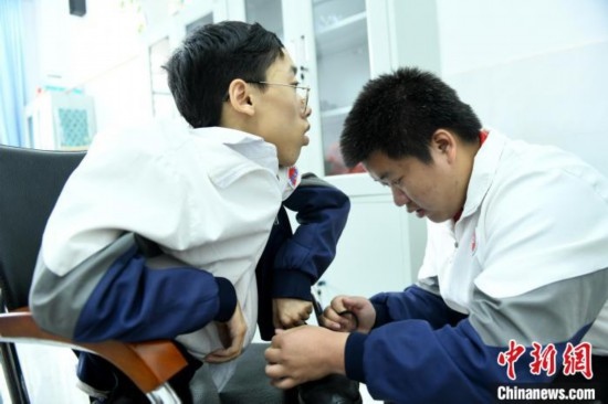 江西省南康中學北校區(qū)的高三學生朱金祥(右)正在給鐘華強(左)系好鞋帶。 卓忠偉 攝
