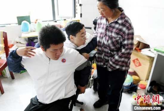 江西省南康中學北校區(qū)的高三學生朱金祥(左)來到學校給鐘華強母子安排的公寓，準備背他去課堂上課。 卓忠偉 攝