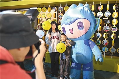 5月7日，在浙江省杭州市湖濱步行街“3D笑臉墻”前，攝影師為游客與杭州亞運(yùn)會(huì)吉祥物之一“宸宸”拍攝合影。