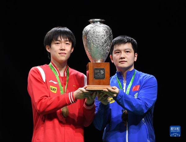 5月27日，樊振東（右）/王楚欽在頒獎儀式上高舉獎杯慶祝。當日，在南非德班進行的2023年世界乒乓球錦標賽男雙決賽中，中國組合樊振東/王楚欽以3比0戰(zhàn)勝韓國組合張禹珍/林鐘勛，奪得冠軍。新華社記者 李亞輝攝