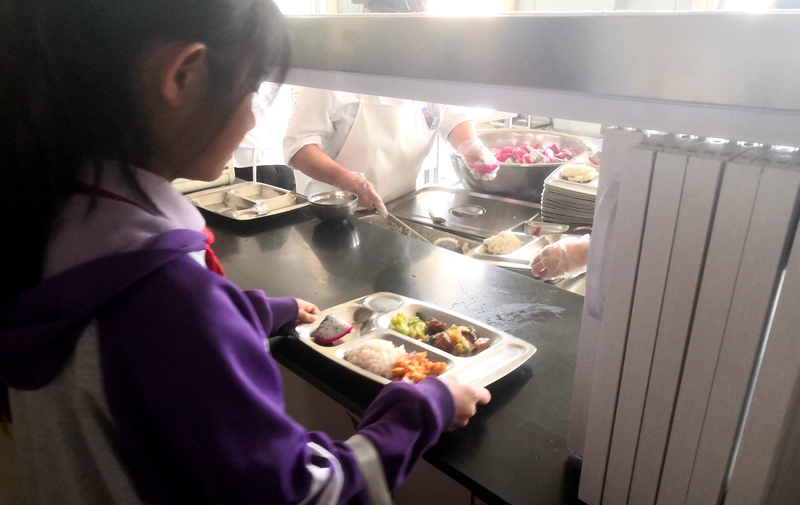 伊金霍洛旗第一小學(xué)學(xué)生正在打飯，今天的飯菜是三菜一湯外加水果，學(xué)生可以多次盛取，吃飽為止。人民網(wǎng)記者 孫博洋攝