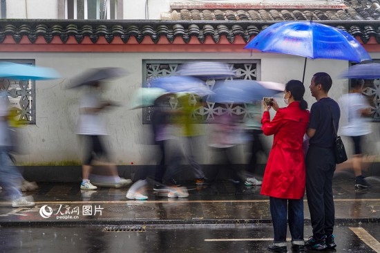 6月7日，在浙江省2023年普通高校招生考試鎮(zhèn)海中學(xué)考點(diǎn)，家長(zhǎng)冒雨目送子女進(jìn)入考場(chǎng)。人民網(wǎng) 章勇濤攝