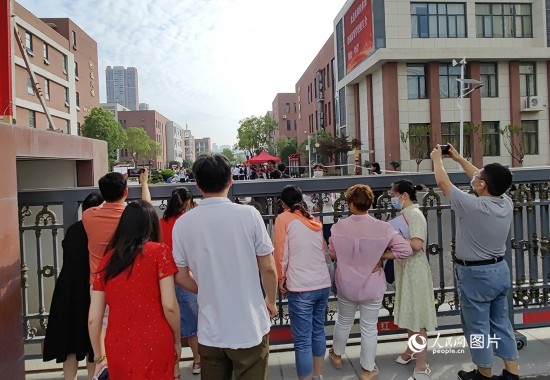 6月7日，武漢市第三中學(xué)考點(diǎn)，考生進(jìn)場(chǎng)后，家長(zhǎng)在柵欄外用手機(jī)拍攝自己的孩子。人民網(wǎng)記者 郭婷婷攝