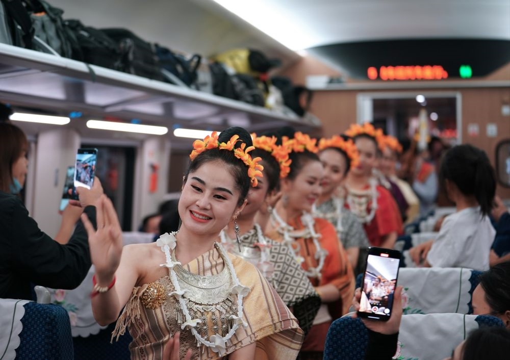 2023年4月13日，老撾工作人員在D887次國際旅客列車上表演。當(dāng)日，中老鐵路從中國昆明南站、老撾萬象站雙向?qū)﹂_D887次和D888次國際旅客列車，兩地乘火車可當(dāng)日通達(dá)。中老鐵路是高質(zhì)量共建“一帶一路”的標(biāo)志性工程。新華社記者 邢廣利 攝
