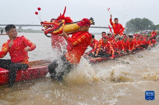 6月22日，在湖南省岳陽市湘陰縣湘江臨資口水域，參加龍舟賽的隊員接“龍頭”下水。
