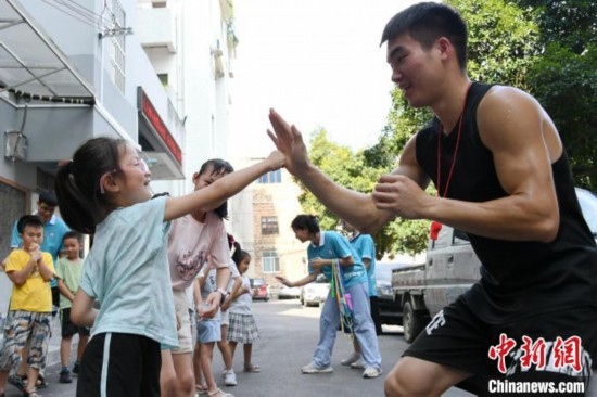 圖為大學(xué)生志愿者在組織孩子們參加體育健身活動。廖光福 攝