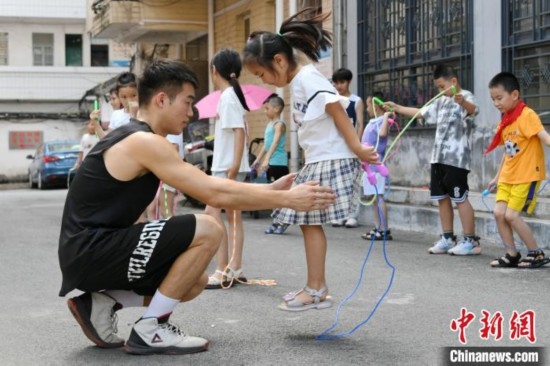 圖為大學(xué)生志愿者在教孩子們學(xué)跳繩。廖光福 攝