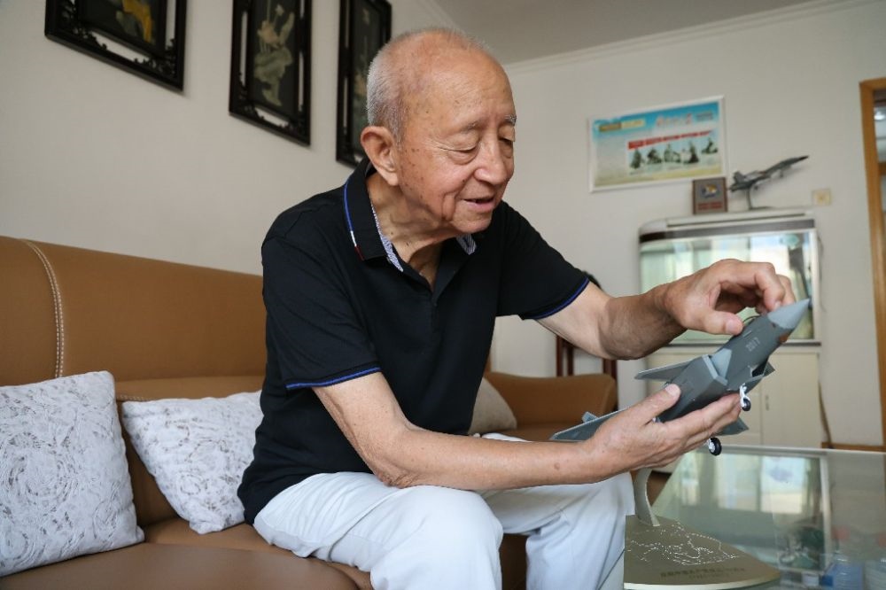 ↑2023年7月24日，新中國(guó)第一代飛行員陶偉在家中擦拭殲-20飛機(jī)模型。新華社發(fā)（張瑞 攝）