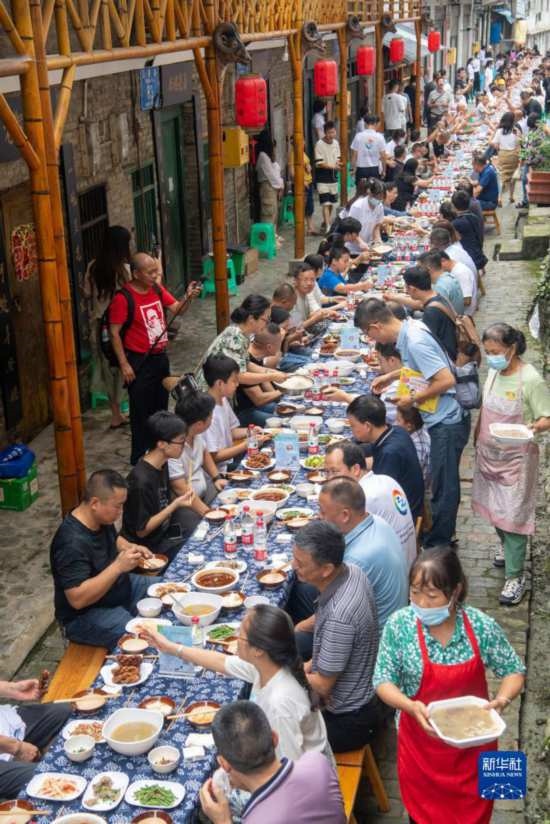 7月29日，在重慶市綦江區(qū)安穩(wěn)鎮(zhèn)，人們在“苗家伏羊節(jié)”上吃長桌宴。新華社記者 唐奕 攝