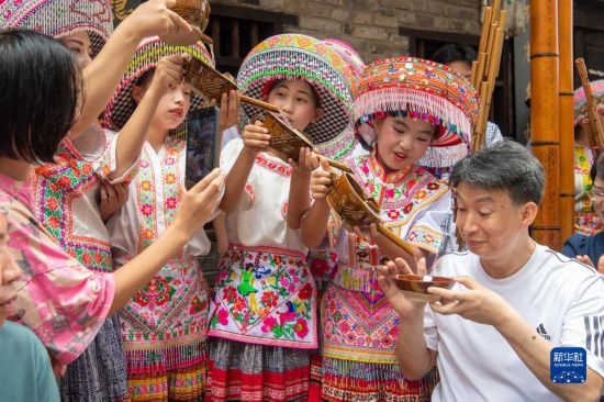 7月29日，在重慶市綦江區(qū)安穩(wěn)鎮(zhèn)，當?shù)鼐用裨凇懊缂曳蚬?jié)”上用傳統(tǒng)習(xí)俗向游客表達祝福。新華社記者 唐奕 攝