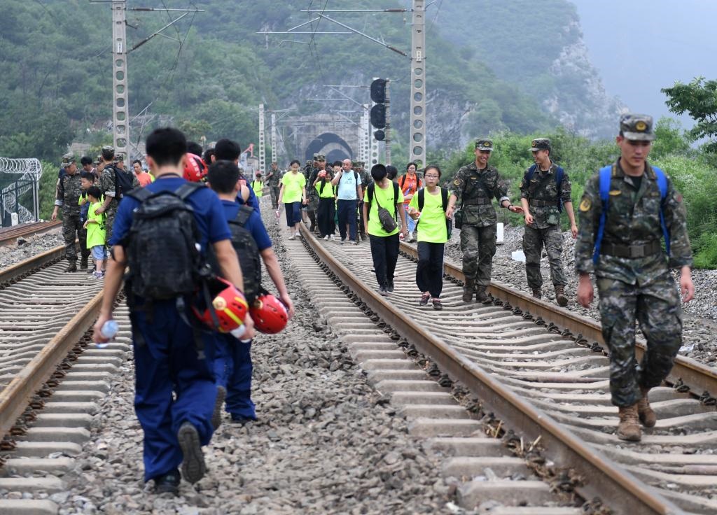 8月2日，部分滯留在北京市門(mén)頭溝山區(qū)受困列車(chē)的旅客，在救援人員幫助下前往轉(zhuǎn)運(yùn)客車(chē)。新華社記者張晨霖 攝