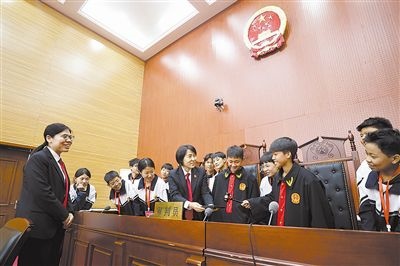 圖③：同學(xué)們穿法袍、敲法槌，爭做“小法官”。