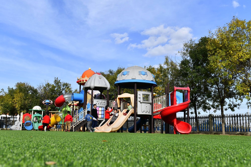 在山東省東營市墾利區(qū)楊廟社區(qū)幼兒園，孩子們在老師的帶領(lǐng)下進行戶外活動（2021年10月19日攝）。新華社記者 郭緒雷 攝