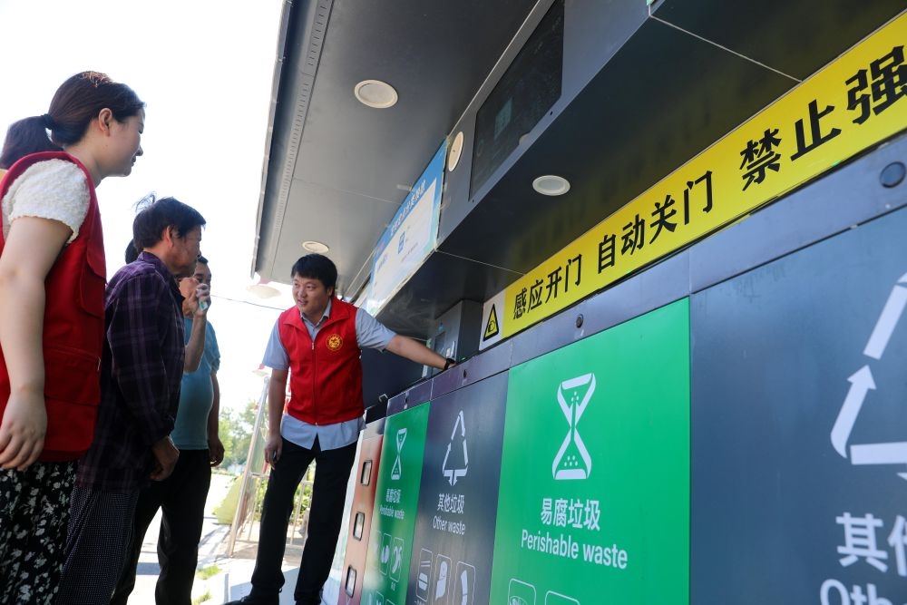 在安徽省合肥市長豐縣莊墓鎮(zhèn)棗林社區(qū)，志愿者指導(dǎo)居民使用智能垃圾分類回收設(shè)備（2023年9月1日攝）。新華社記者 曹力 攝