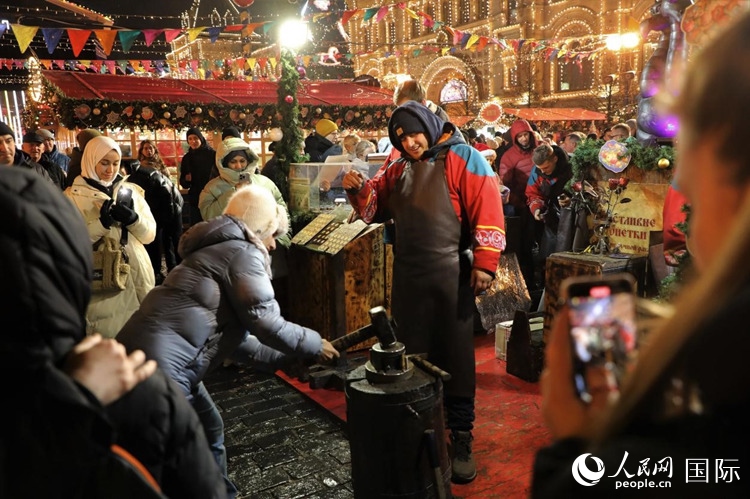 游客在新年集市上體驗制作紀(jì)念幣。人民網(wǎng)記者 隋鑫攝