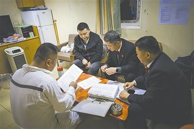 圖②：法官向船長講解相關(guān)法律規(guī)定，查看船舶資料，并與船方辦理扣押船舶的手續(xù)。