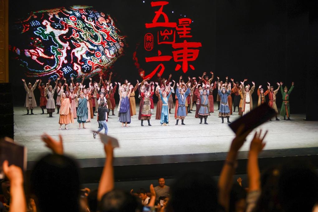 2023年7月31日，新疆和田地區(qū)新玉歌舞團(tuán)在烏魯木齊京劇院演出舞劇《五星出東方》后和觀眾互相揮手致意。這場(chǎng)演出是第六屆中國(guó)新疆國(guó)際民族舞蹈節(jié)的參演劇目之一，曾榮獲國(guó)家“文華獎(jiǎng)”等。新華社記者 郝昭 攝