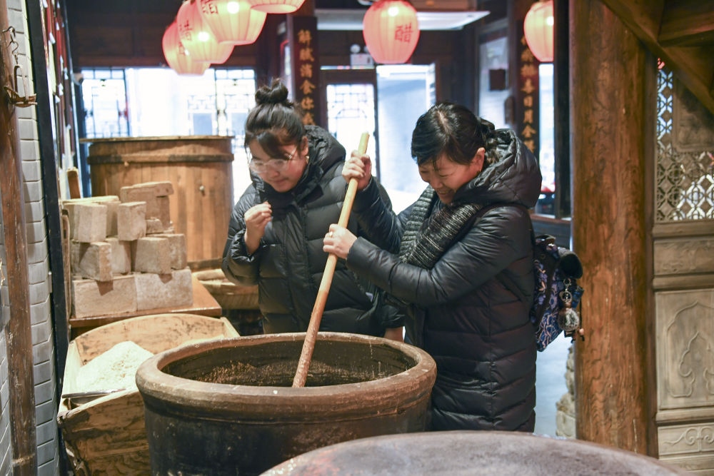 游客在平遙古城東湖老醋坊內(nèi)體驗陳醋發(fā)酵打耙（2022年1月28日攝）。新華社發(fā)（梁生仁攝）