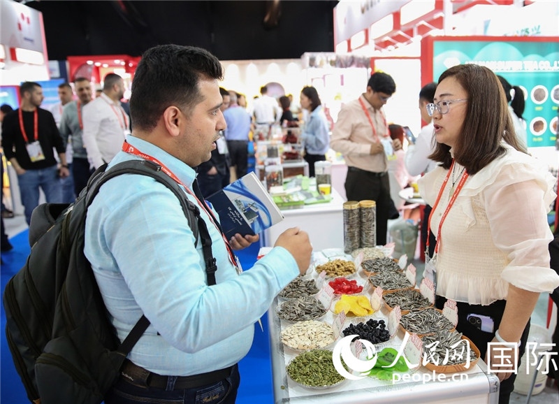 圖為一家中國干果參展企業(yè)代表與采購商洽談。人民網(wǎng) 塔里克·易卜拉欣攝