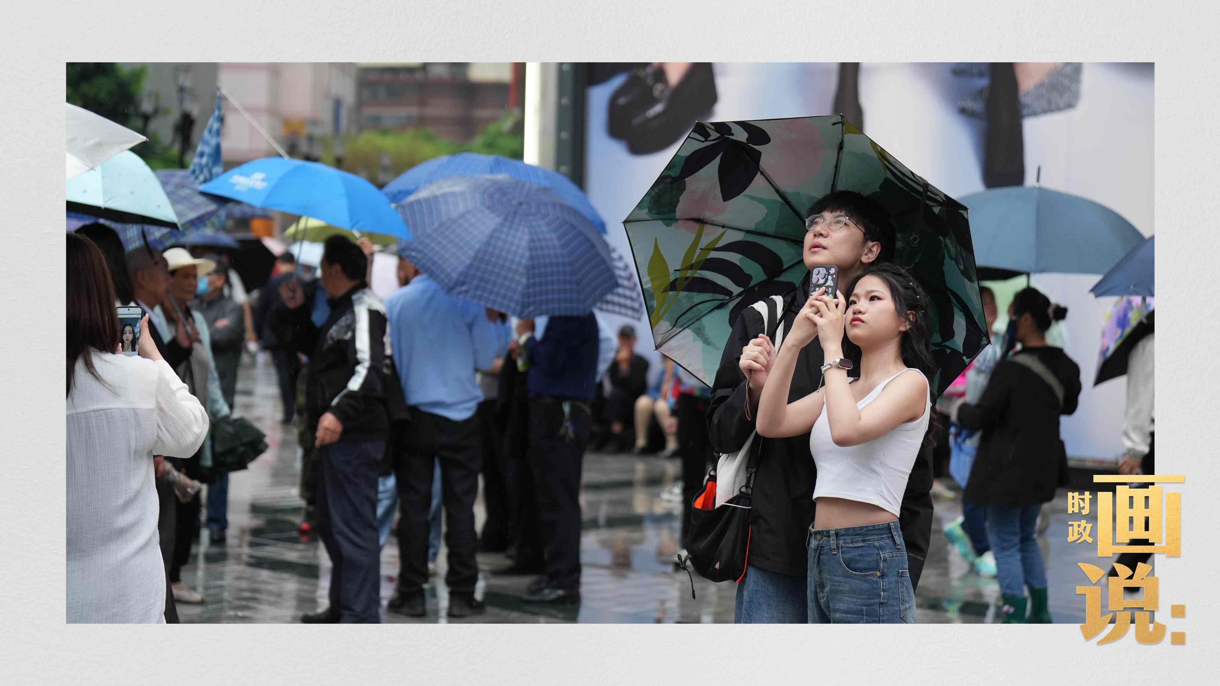 △細(xì)雨中的解放碑步行街，騎在父親肩膀的小女孩好奇張望。
