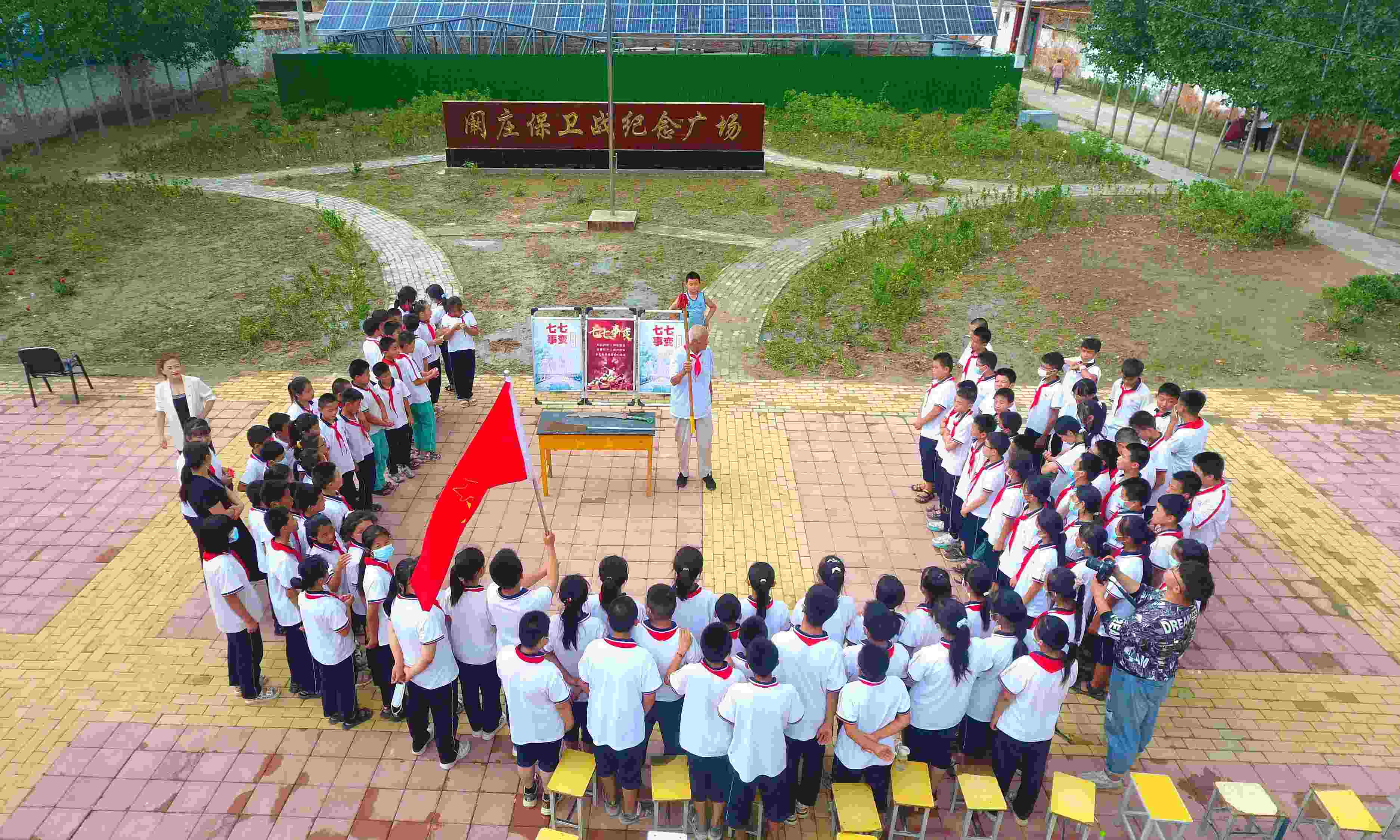 2022年7月6日，山東省聊城市，在茌平區(qū)菜屯鎮(zhèn)闞莊村的闞莊保衛(wèi)戰(zhàn)紀念廣場，闞莊保衛(wèi)戰(zhàn)親歷者王光木老人為小學生們講述抗戰(zhàn)故事，展示大刀、長矛。