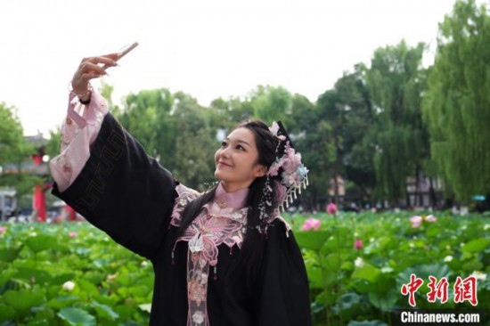 6月19日，時值一年畢業(yè)季，四川大學(xué)望江校區(qū)荷花池里的荷花盛開，成為了畢業(yè)生們的打卡圣地，吸引了眾多畢業(yè)生拍照留念。圖為畢業(yè)生在荷花池邊拍照留念。中新社記者 安源 攝