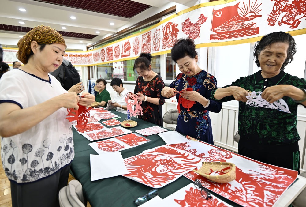 6月19日，長(zhǎng)城花園社區(qū)居民在社區(qū)“才藝堂”制作剪紙。