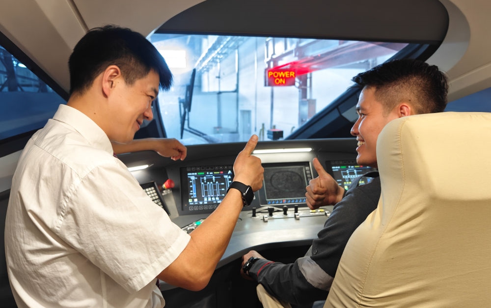 2023年8月25日，在印度尼西亞萬隆的雅萬高鐵德卡魯爾動車所內(nèi)，中國師傅穆振（左）向印尼火車司機(jī)塞蒂亞萬講解動車組出庫前的上電作業(yè)。新華社記者 徐欽 攝