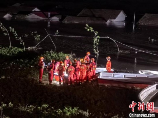  7月6日凌晨3時(shí)，在湖南岳陽(yáng)華容縣團(tuán)洲垸洞庭湖一線堤防，救援人員剛剛完成一次救援任務(wù)，遠(yuǎn)處是被淹的民房。中新社記者 白祖偕 攝