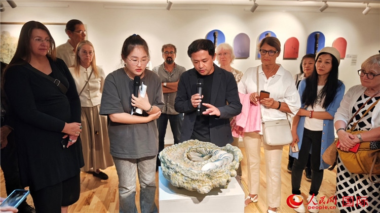 參展人、景德鎮(zhèn)陶瓷大學(xué)設(shè)計藝術(shù)學(xué)院副院長余劍峰（中）向來賓介紹參展作品。人民網(wǎng)記者 殷淼攝