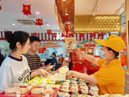 北京稻香村一家門店內(nèi)，售貨員向顧客展示新上市的月餅禮盒。（受訪者供圖）