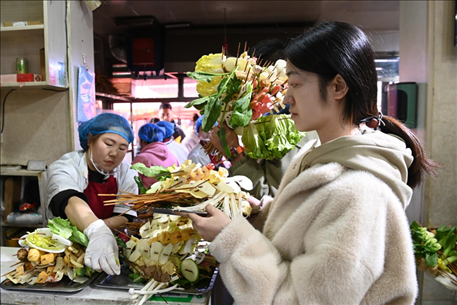 游客挑選好麻辣燙菜品后排隊等待加工。新華社記者 范培珅 攝