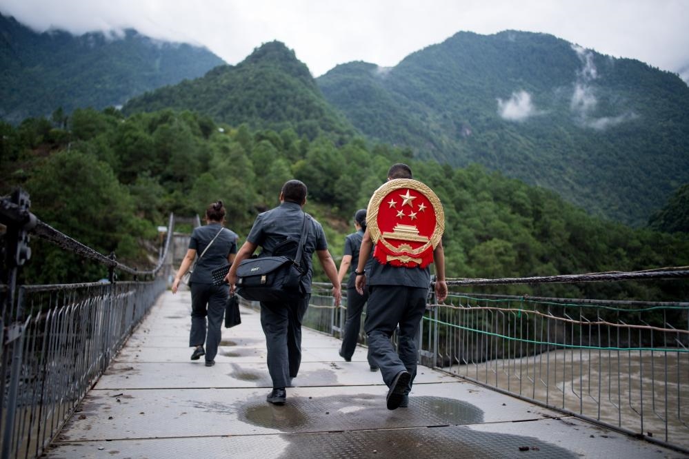 云南省怒江傈僳族自治州貢山縣人民法院法官鄧興背著國徽與同事們跨過怒江（2019年8月30日攝）。怒江高山峽谷眾多，交通不便，為方便群眾、更好地開展法律服務(wù)，背著國徽攀高山、過索橋、躲落石、鉆老林……成為鄧興法官的工作常態(tài)。新華社記者 江文耀 攝