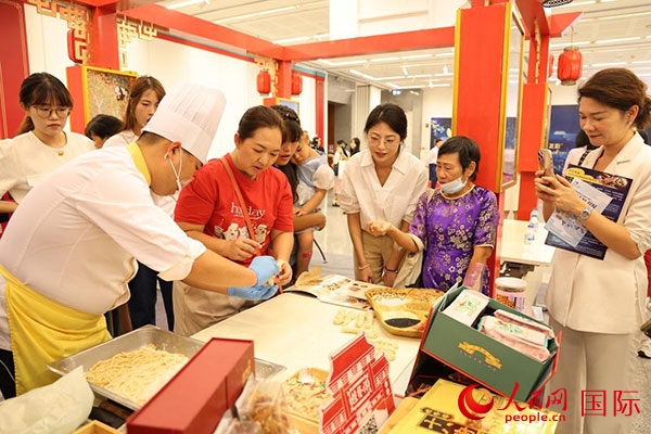 演出前，在天津桂發(fā)祥十八街麻花制作技藝非遺體驗展臺前，泰國民眾體驗天津麻花制作。人民網記者 楊一攝
