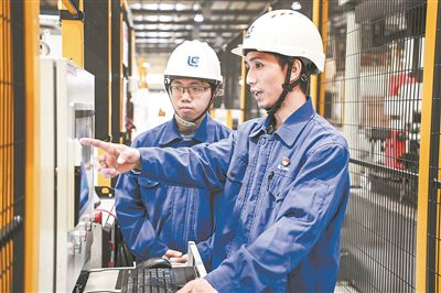 在廣西柳工機械股份有限公司生產(chǎn)車間內(nèi)，一名高級技師（右）給徒弟講解數(shù)控設(shè)備操作細節(jié)。新華社記者 曹祎銘攝
