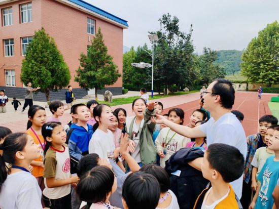 孩子們?cè)诓賵?chǎng)和老師一起試飛無人機(jī)（沈怡辰 攝）
