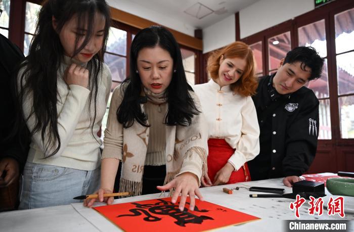 1月20日，西泠印社社員李硯（左二）為外籍留學(xué)生講述蛇年福字貼創(chuàng)作靈感。當(dāng)日，來自巴西、馬來西亞、加納、哈薩克斯坦的外籍留學(xué)生在浙江杭州西泠印社體驗(yàn)福貼、春聯(lián)和篆刻，感受古老的中國傳統(tǒng)文化。中新社記者 王剛 攝