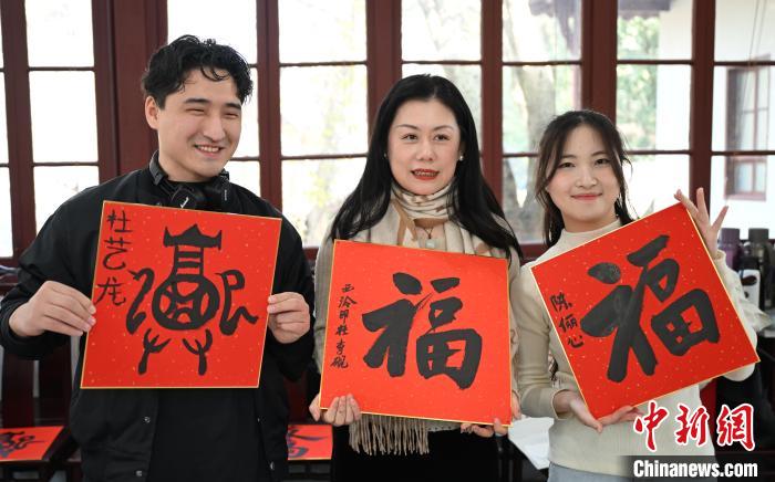 1月20日，外籍留學(xué)生和西泠印社社員李硯(中)展示各自創(chuàng)作的福貼。當(dāng)日，來自巴西、馬來西亞、加納、哈薩克斯坦的外籍留學(xué)生在浙江杭州西泠印社體驗(yàn)福貼、春聯(lián)和篆刻，感受古老的中國傳統(tǒng)文化。中新社記者 王剛 攝