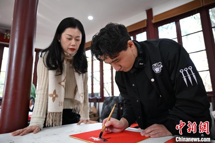 1月20日，外籍留學(xué)生在西泠印社社員李硯指導(dǎo)下寫福。當(dāng)日，來自巴西、馬來西亞、加納、哈薩克斯坦的外籍留學(xué)生在浙江杭州西泠印社體驗(yàn)福貼、春聯(lián)和篆刻，感受古老的中國傳統(tǒng)文化。中新社記者 王剛 攝
