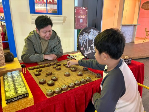 柯秋楓與市民下椰雕象棋。人民網(wǎng) 陳葉欣攝