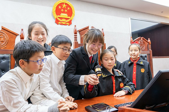 圖①：干警帶同學(xué)們體驗(yàn)敲法槌。