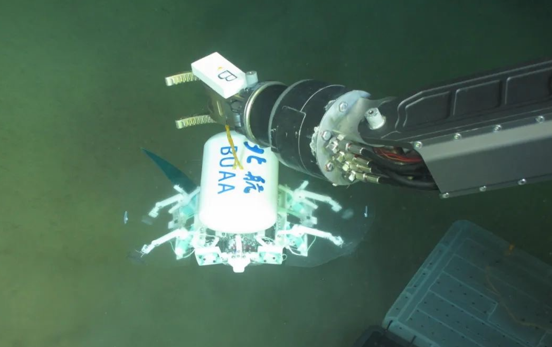 科研人員利用機械臂將北航深海小型機器人投于馬里亞納海溝。校方供圖
