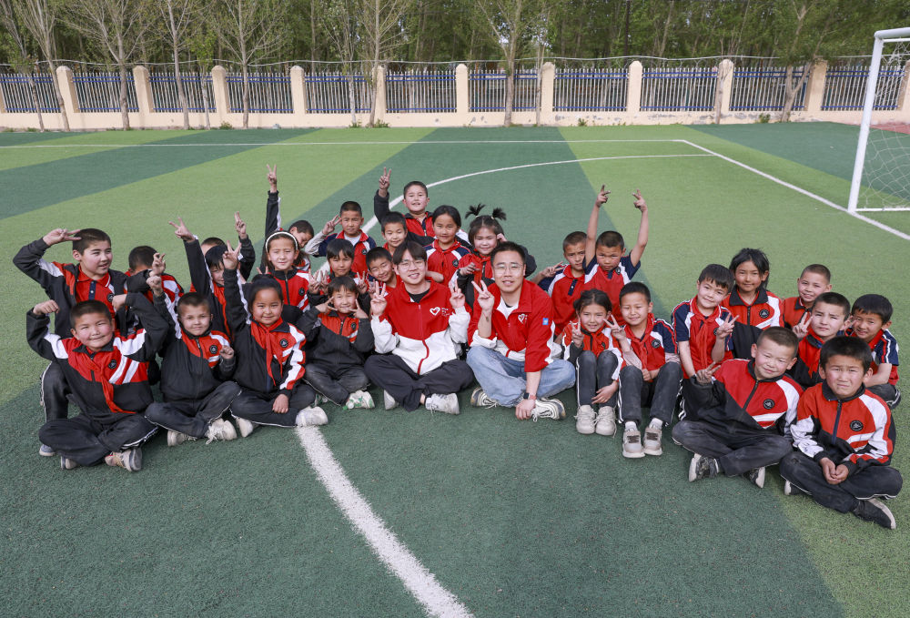 4月23日，在新疆克州阿圖什市哈拉峻鄉(xiāng)謝依特小學(xué)，支教教師王俊文（中左）、李軻凡（中右）和學(xué)生在一起。